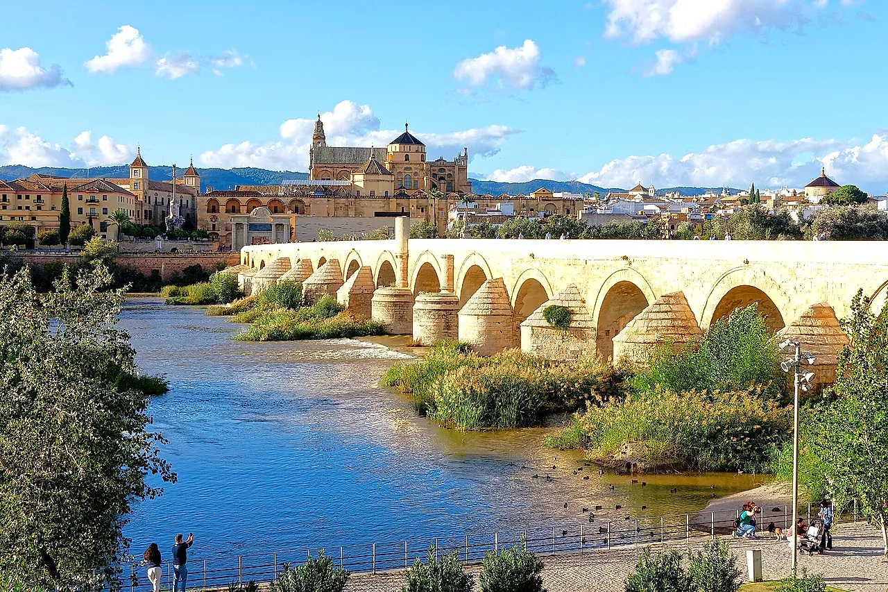 The Roman Bridge over the Guadalquivir with the Mosque-Cathedral and the old town of Córdoba rising behind it under a blue sky