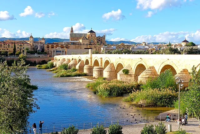 The Roman Bridge over the Guadalquivir with the Mosque-Cathedral and the old town of Córdoba rising behind it under a blue sky